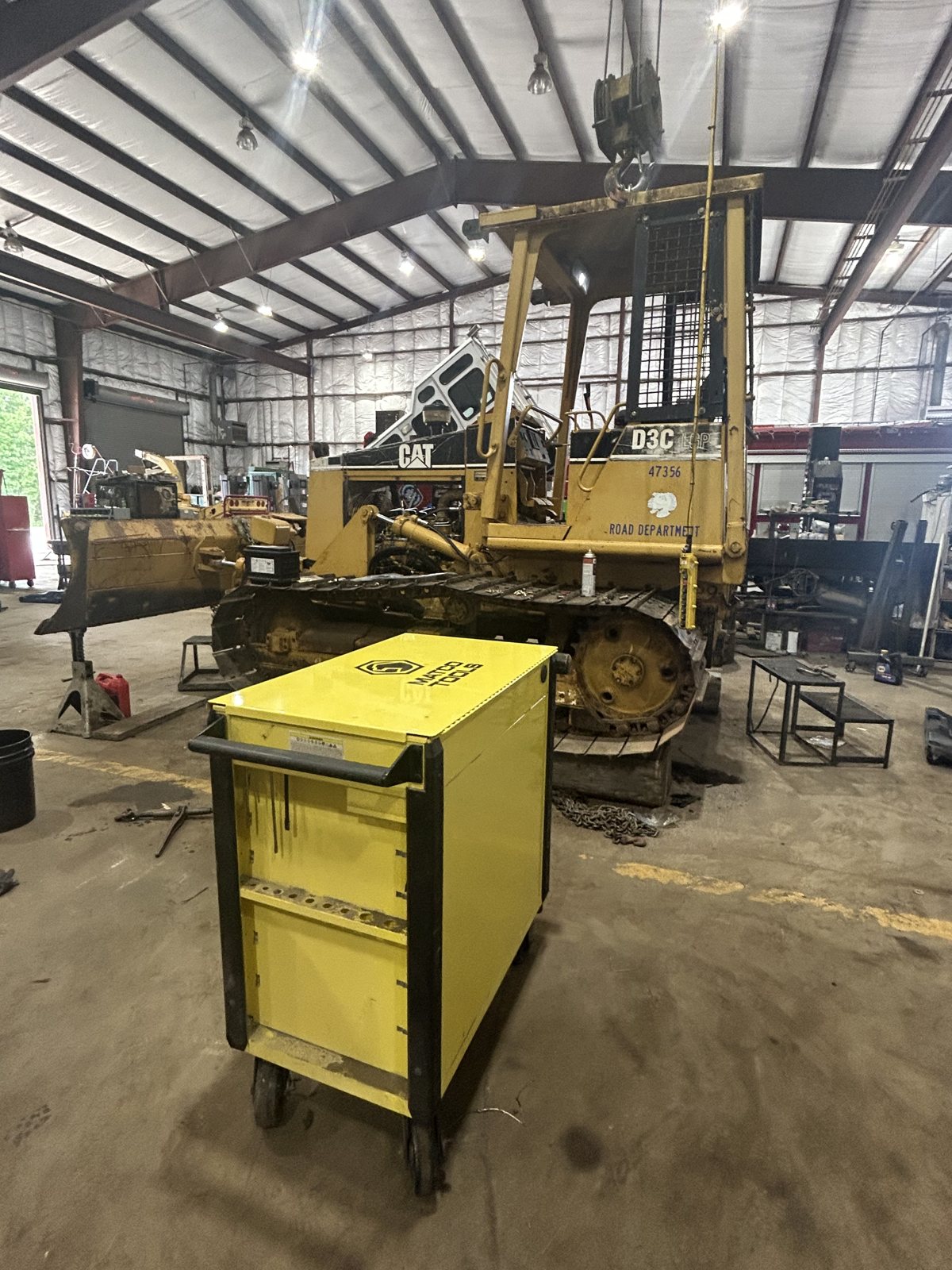 Yellow tool cabinet with a crawler loader behind it