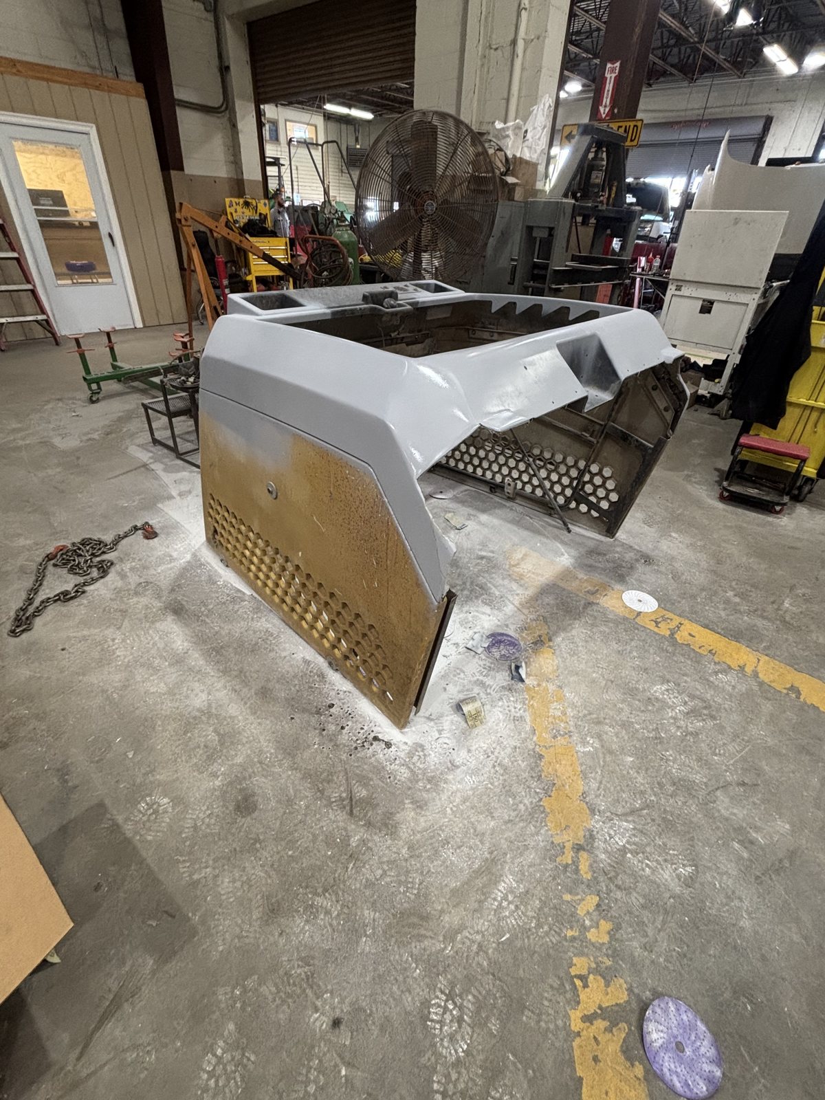Refinished equipment hood panel with a lift in the background