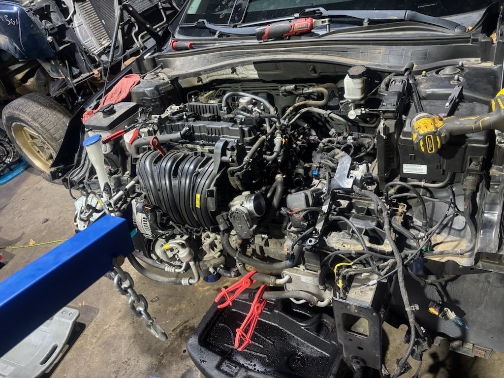 Engine bay with the engine removed, car on a lift.